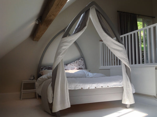 Grey four poster bed with drapes and bent posts